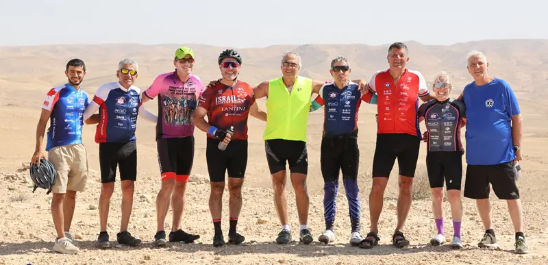 Nine cyclists standing in a line in the desert